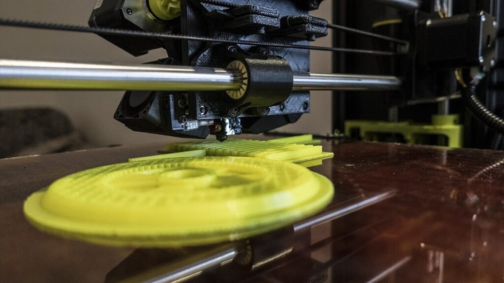 Głowica drukarki 3D nad żółtym, pierścieniowym wydrukiem na szklanym stole